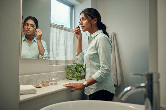 Woman doing quick morning makeup at a bathroom mirror before work